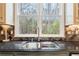 Close-up of a kitchen sink area featuring a large window, stainless steel sink, modern faucet, and stylish backsplash at 5170 Deerlake Dr, Alpharetta, GA 30005