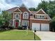 Beautiful two-story brick home with a well-manicured lawn, two car garage, and red shutters on the windows at 3302 Fieldwood Se Dr, Smyrna, GA 30080