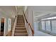Carpeted staircase leading to upper level, adjacent to dining room with hardwood floors and large windows at 3302 Fieldwood Se Dr, Smyrna, GA 30080