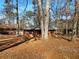 Ranch home with brick exterior surrounded by tall trees and a yard covered in leaves at 4227 Pine Cir, Forest Park, GA 30297