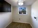 Cozy laundry room with wood-look flooring, a window, dark cabinets, and modern light fixture at 1376 Cornwall Rd, Decatur, GA 30032