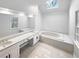 Bright bathroom featuring a skylight, soaking tub, and dual vanity sinks at 1302 Milstead Ne Trce, Marietta, GA 30066
