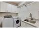 Modern laundry room features washer, dryer, sink and storage cabinets at 1537 Harts Mill Ne Rd, Brookhaven, GA 30319