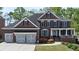 Charming brick home featuring a manicured lawn, inviting porch, and a spacious three-car garage at 2875 Ivy Brook Ln, Buford, GA 30519