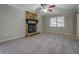 Bright living room featuring a stone fireplace, carpet flooring, and a ceiling fan at 169 Holly Ct, Loganville, GA 30052