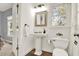 Bright bathroom featuring a classic pedestal sink, toilet, and a window with natural light at 672 Red Sunset Cir, Powder Springs, GA 30127