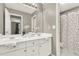 Well-lit bathroom featuring double sinks, a large mirror, and a shower with a colorful polka dot curtain at 672 Red Sunset Cir, Powder Springs, GA 30127