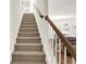 Carpeted staircase with wooden handrail leading to the upper level of this home at 672 Red Sunset Cir, Powder Springs, GA 30127