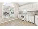 Bright kitchen featuring white cabinets, modern appliances, and large window for natural light at 2414 Clock Face Ct, Lawrenceville, GA 30043