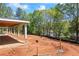 A spacious backyard with a covered patio area under construction, surrounded by lush trees and a partially fenced perimeter at 4238 Hamilton Mill Rd, Buford, GA 30519