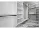 Spacious walk-in closet with custom white shelving and drawers and stylish marble flooring at 4238 Hamilton Mill Rd, Buford, GA 30519