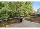 A backyard deck with wood railing overlooks a green, wooded area. It has a grill at 625 Jefferson Pl, Cumming, GA 30040