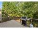 A backyard deck with wood railing overlooks a green, wooded area. It has a grill at 625 Jefferson Pl, Cumming, GA 30040