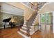 Foyer featuring wood staircase, entry to living room, and hardwood floors at 625 Jefferson Pl, Cumming, GA 30040