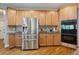 Kitchen with stainless steel refrigerator, built-in oven, light wood cabinets, and granite countertops at 625 Jefferson Pl, Cumming, GA 30040