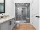 Modern bathroom featuring a glass-enclosed shower, marble countertop, and sleek gray cabinets at 1355 Cashiers Way, Roswell, GA 30075