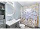 Bathroom featuring a gray vanity, round mirror, decorative shower curtain, and updated lighting at 1646 Flicker Rd, Jonesboro, GA 30238