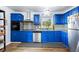 Bright kitchen featuring modern appliances, blue cabinets, gray backsplash, granite countertops, and updated flooring at 1646 Flicker Rd, Jonesboro, GA 30238