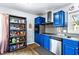 View of kitchen with stainless steel appliances, blue cabinets, floating shelves, and a window at 1646 Flicker Rd, Jonesboro, GA 30238