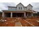 Under-construction two-story home featuring a three-car garage with stone accents and a covered porch at 4830 Briscoe Dr, Cumming, GA 30028