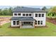 A view of the rear exterior showcasing a covered porch, large windows, gray siding and a well manicured green lawn at 4830 Briscoe Dr, Cumming, GA 30028
