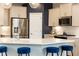 A modern kitchen features stainless steel appliances, a white countertop, and elegant blue bar stools at 222 Ellis Ln, Woodstock, GA 30189