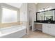 Bright bathroom with a soaking tub and a vanity with a black granite countertop at 648 Ocean Ave, Canton, GA 30114