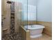 Bright bathroom featuring a glass-enclosed shower, freestanding tub, and travertine tile at 76 Misty View Ln, Acworth, GA 30101