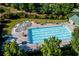 Aerial view of community swimming pool, splash pad, seating area with umbrellas and manicured lawn at 76 Misty View Ln, Acworth, GA 30101