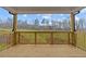 Covered back porch with a wood railing overlooking the backyard and trees at 4770 Briscoe Dr, Cumming, GA 30028