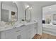 Elegant bathroom featuring dual sinks, marble countertops, modern gold fixtures, and white cabinets at 1040 Millridge Se Ln, Marietta, GA 30067