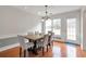 A dining area featuring hardwood floors, a modern chandelier, and natural light from the adjacent door and windows at 2685 Archer Way, Dacula, GA 30019