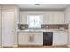 Well-lit kitchen with white cabinetry, mosaic backsplash, and stainless steel sink at 2685 Archer Way, Dacula, GA 30019
