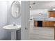Comfortable powder room area with pedestal sink, large mirror, and access to open-plan kitchen at 2010 Skylar Leigh Dr, Buford, GA 30518