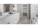 Luxurious bathroom featuring dual sinks, white cabinetry, tile flooring, and a view of a spacious walk-in closet at 242 Crestbrook Ln, Dallas, GA 30157