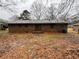 Rear exterior view of brick home, with trees, small patio area and level yard at 3450 Estes Dr, Atlanta, GA 30349
