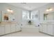 Bright bathroom featuring dual sinks, a soaking tub, and white tile flooring at 200 Edinburgh Ln, Woodstock, GA 30188