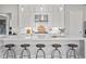 Modern kitchen island features bar stool seating, a stainless steel sink, and sleek white cabinets with pendant lighting at 3539 Cedarvale Ct, Powder Springs, GA 30127