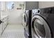 Bright laundry room with white cabinets, patterned tile floors, and high-efficiency washer/dryer units at 1297 Swims Valley Nw Dr, Atlanta, GA 30327