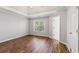 Light-filled bedroom featuring tray ceilings, hardwood floors, a large window and closet doors at 2075 Pine Tree Dr # D4, Buford, GA 30518