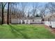 Exterior view of the home with a large, green backyard featuring an outdoor patio with white curtains at 5079 Ne Dogwood Hills Dr, Buford, GA 30518