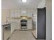 Well-lit kitchen features stainless steel appliances, white cabinetry, and tile flooring at 1150 Strath Clyde Way, Mcdonough, GA 30253