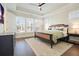 Bright bedroom featuring a dark wood frame bed, tray ceiling, ceiling fan, and natural light from the windows at 720 Tannery Cmn, Alpharetta, GA 30009