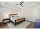 Bright bedroom featuring a dark wood frame bed, tray ceiling, ceiling fan, and natural light from the windows at 720 Tannery Cmn, Alpharetta, GA 30009