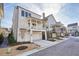 New construction home shows elevated porch and garage entry with a view of other homes in the neighborhood at 720 Tannery Cmn, Alpharetta, GA 30009