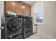 Modern laundry room with front-load washer and dryer and custom cabinets above at 720 Tannery Cmn, Alpharetta, GA 30009