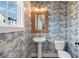 Charming powder room featuring a pedestal sink, decorative mirror, and patterned wallpaper at 120 Pinecone Pkwy, Alpharetta, GA 30022