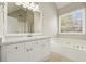 Bathroom showcasing double sink vanity, tile flooring, and a soaking tub beneath a bright window at 4074 Gold Mill Rdg, Canton, GA 30114