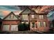 Charming two-story brick home features an attached two-car garage, shuttered windows, and mature landscaping at 4074 Gold Mill Rdg, Canton, GA 30114