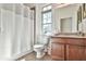 Bright bathroom with a white shower curtain, neutral paint, wooden vanity, and window with backyard views at 2817 Middlecreek Way # 1703, Cumming, GA 30041